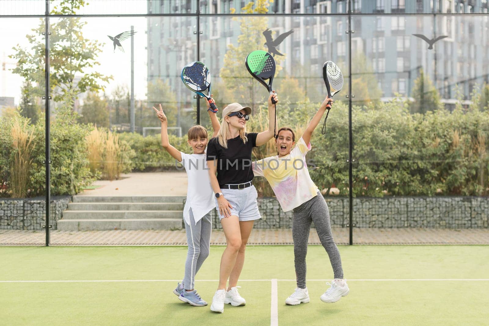 Active young woman practicing Padel Tennis with group of players in the tennis court outdoors by Andelov13