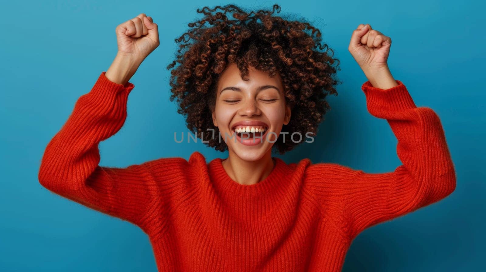 A woman in a red sweater celebrating with her hands up