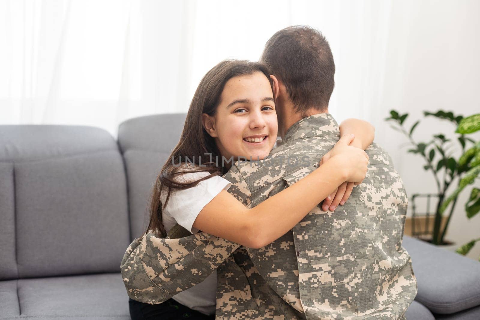 Young man in military uniform with his wife on sofa at home by Andelov13