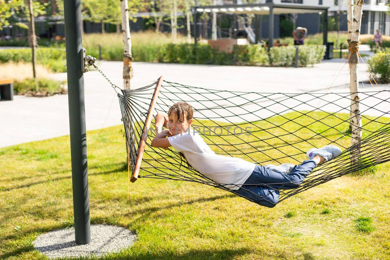 happy cheerful child smiling and lying, resting in a hammock in the woods in a glade in summer among the bright green grass. High quality photo