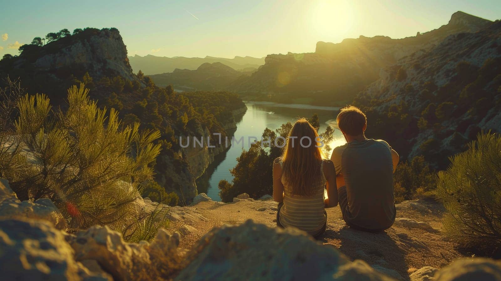 A couple sitting on a rock overlooking the water and mountains