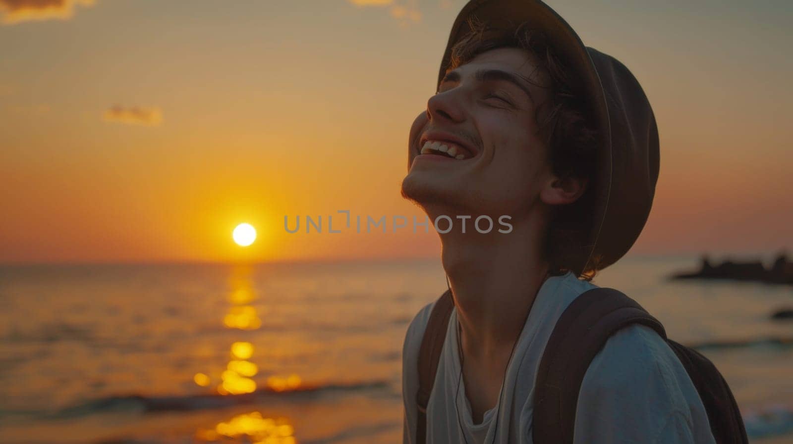 A man with a hat on smiling at the sun