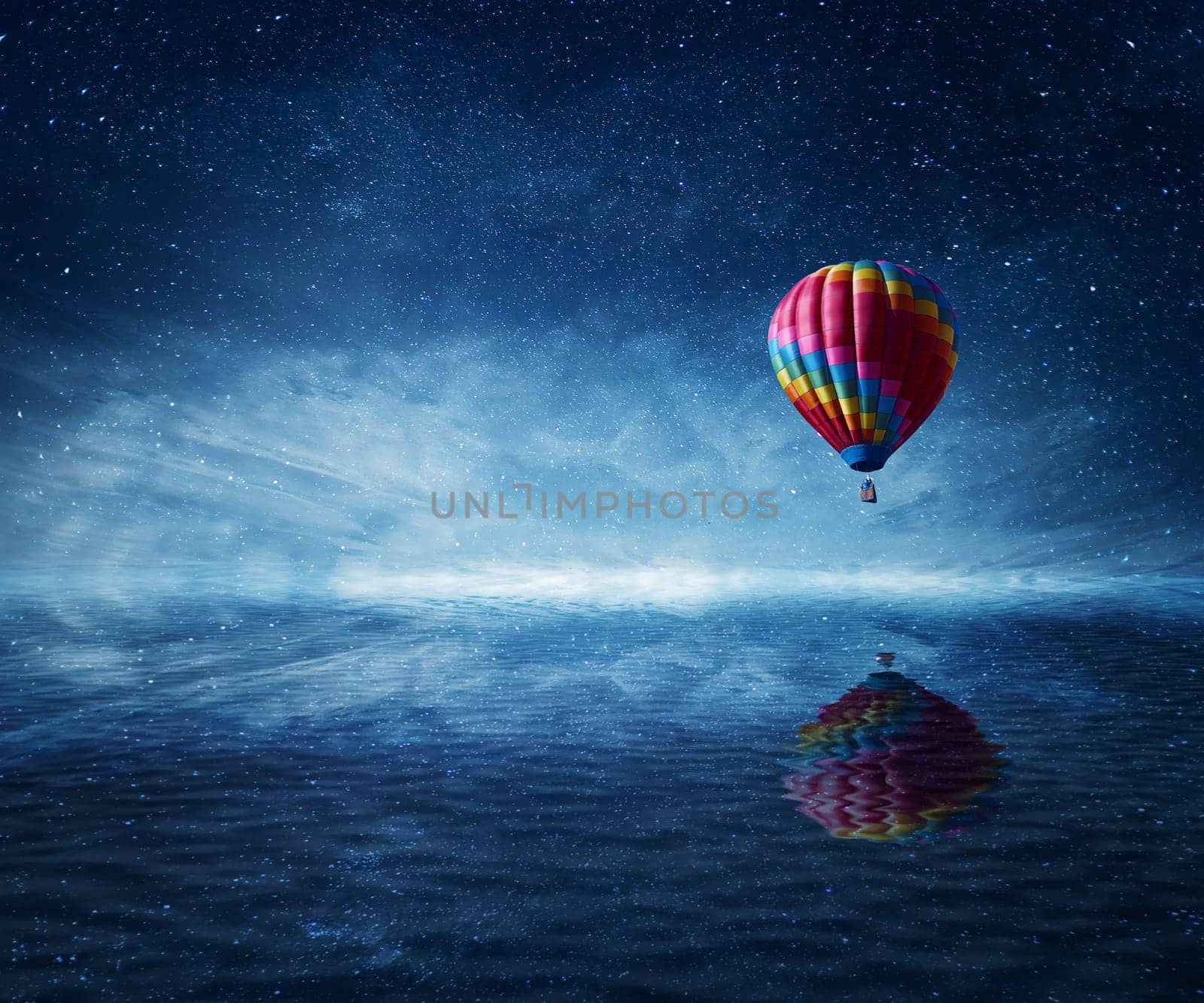 Hot air balloon flying over the a cold dark blue sea. Wonderful landscape with a starry night sky background and water reflection.