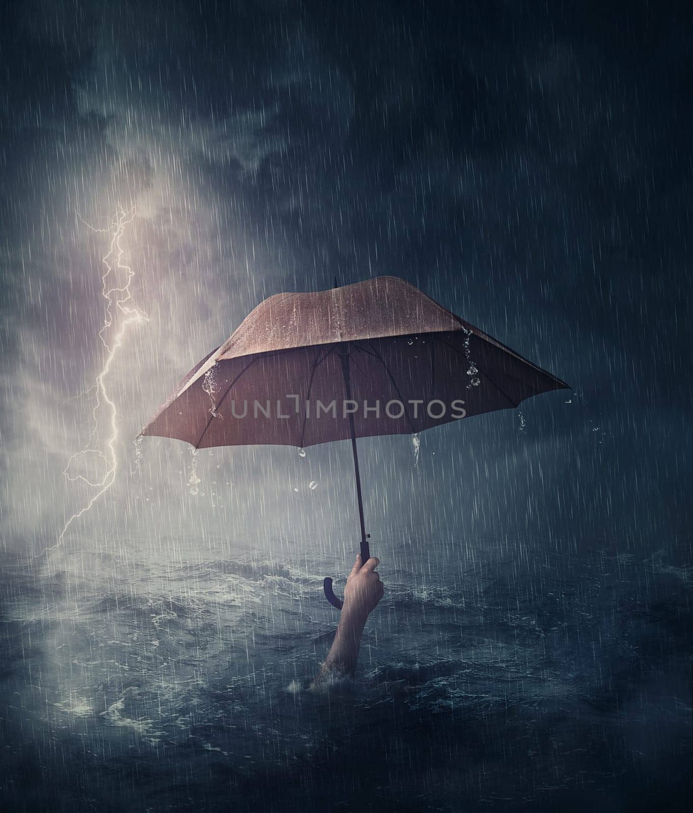 Human hand holding an umbrella sinking in the ocean. Surreal and dramatic scene of person drowning in the sea waters under the storm. Business despair and failure metaphor. Crisis problems concept by psychoshadow