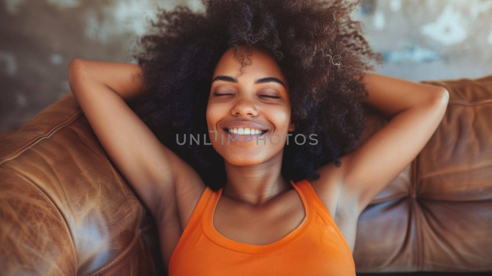 A woman with curly hair laying on a couch smiling