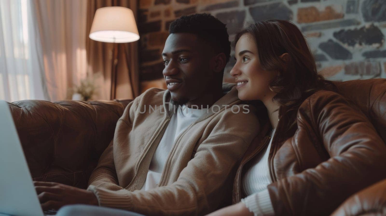 A man and woman sitting on a couch looking at their laptop