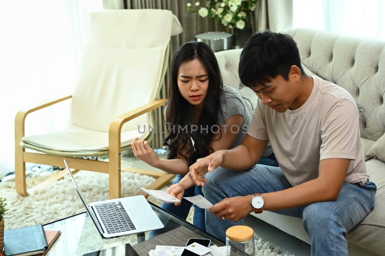 Serious young married couple checking their domestic bills and calculating family budget at home.
