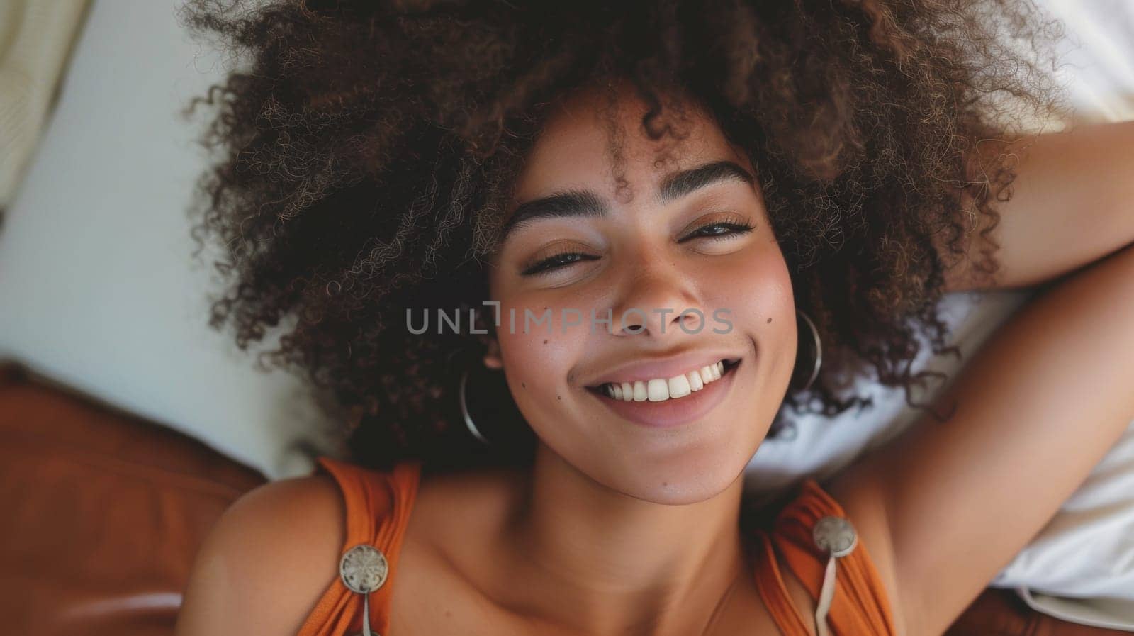 A woman with large afro smiling while laying on a bed