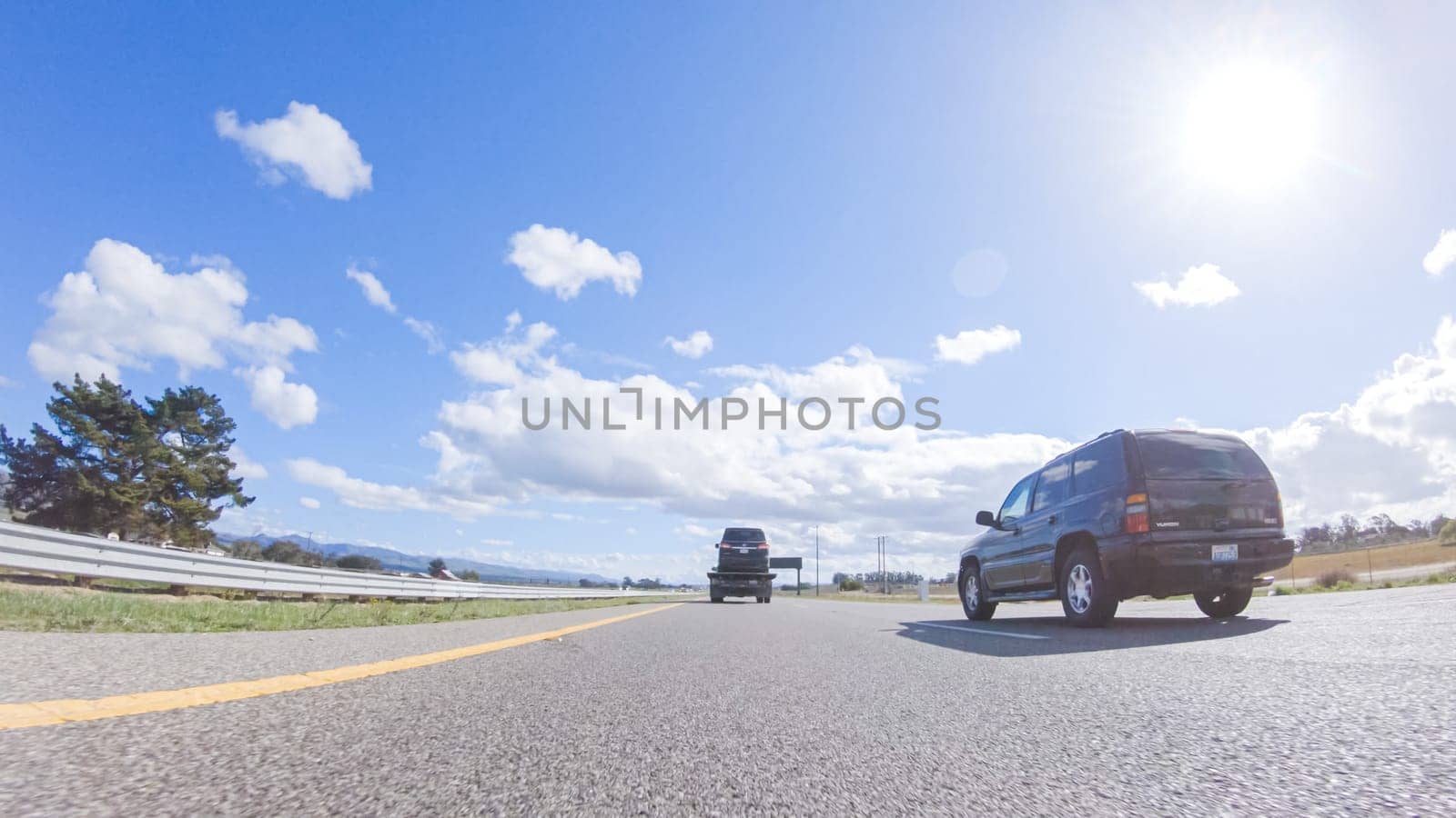 Santa Maria, California, USA-December 6, 2022-On a clear winter day, a car smoothly travels along Highway 101 near Santa Maria, California, under a brilliant blue sky, surrounded by a blend of greenery and golden hues.