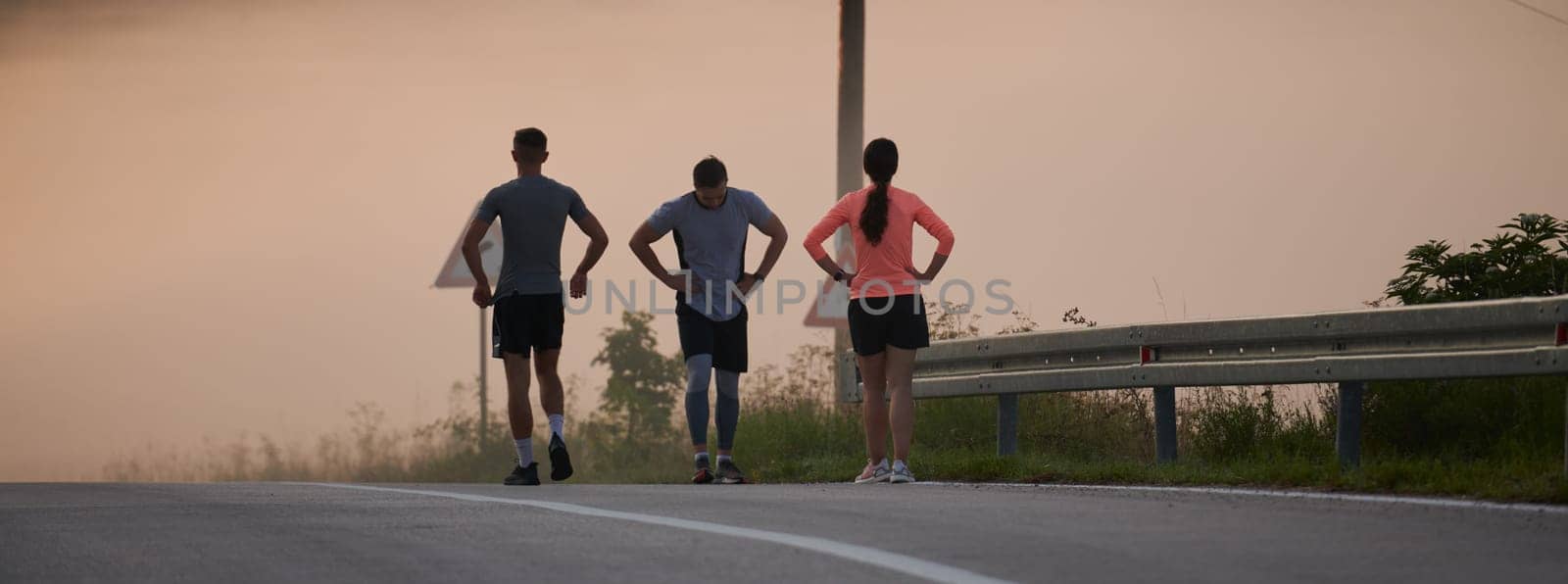 A group of friends, athletes, and joggers embrace the early morning hours as they run through the misty dawn, energized by the rising sun and surrounded by the tranquil beauty of nature by dotshock
