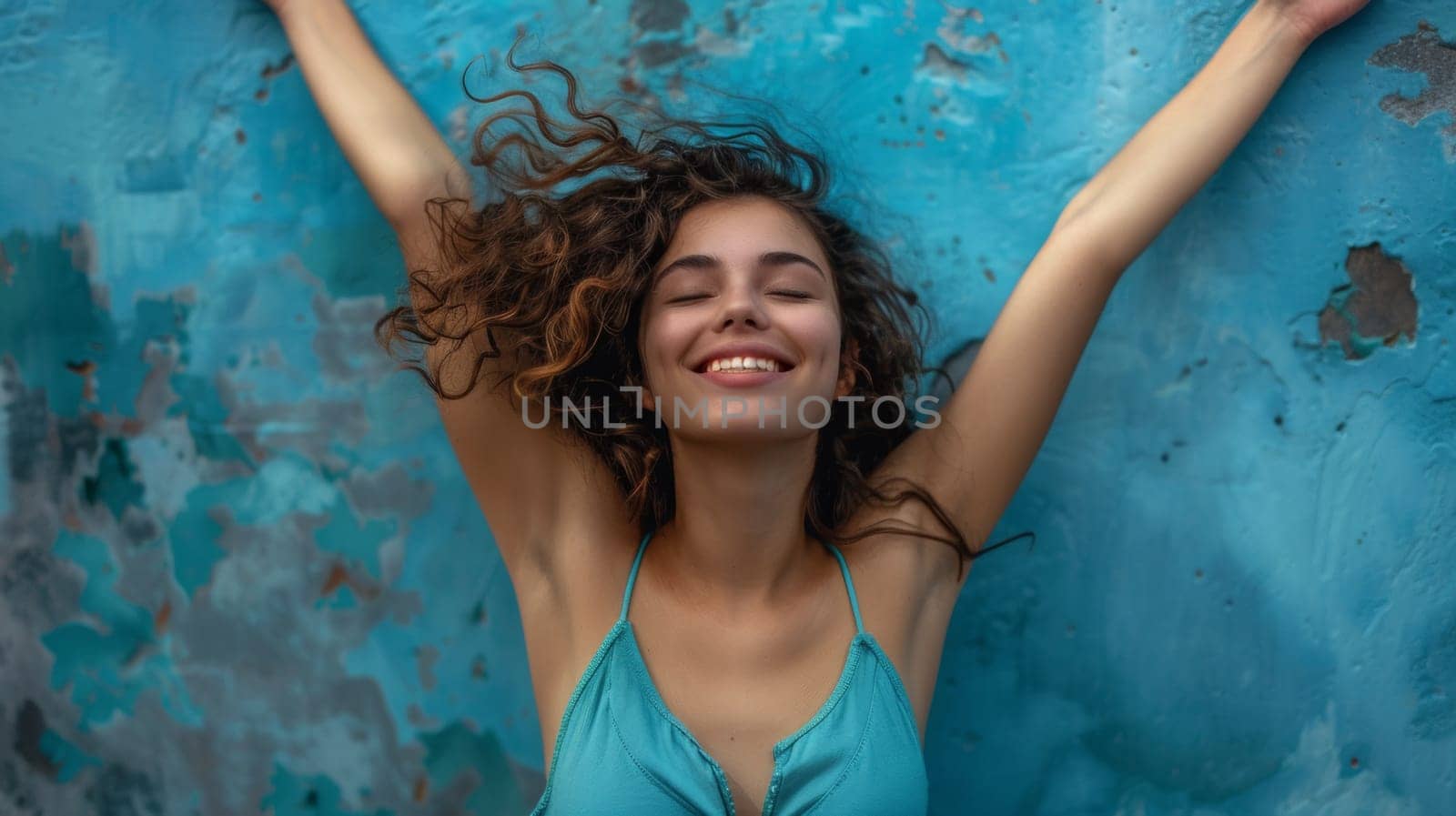 A woman in a blue bikini smiling with her arms outstretched