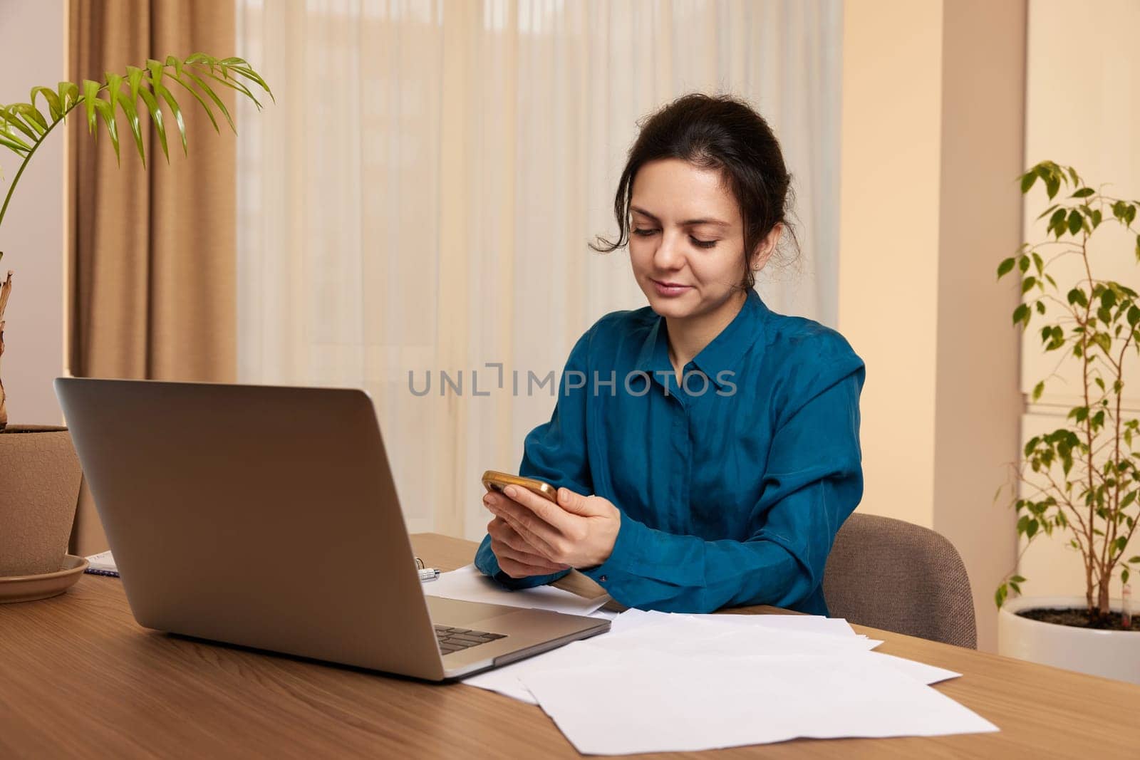 businesswoman working on laptop and using phone at home by erstudio