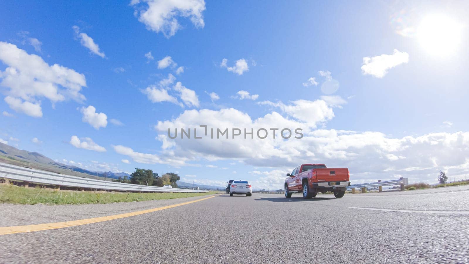 Santa Maria, California, USA-December 6, 2022-On a clear winter day, a car smoothly travels along Highway 101 near Santa Maria, California, under a brilliant blue sky, surrounded by a blend of greenery and golden hues.