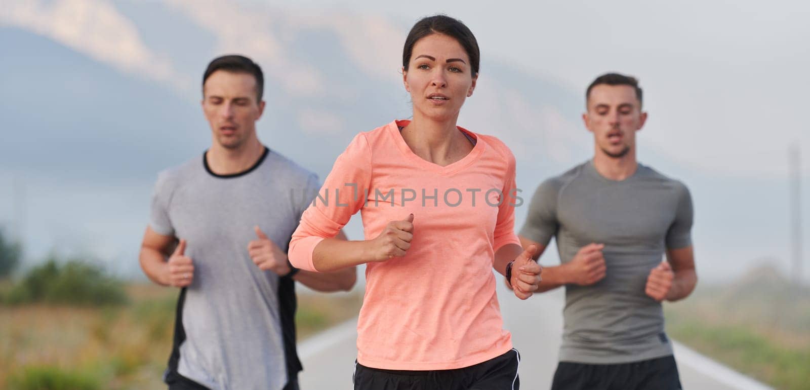 A group of friends, athletes, and joggers embrace the early morning hours as they run through the misty dawn, energized by the rising sun and surrounded by the tranquil beauty of nature.