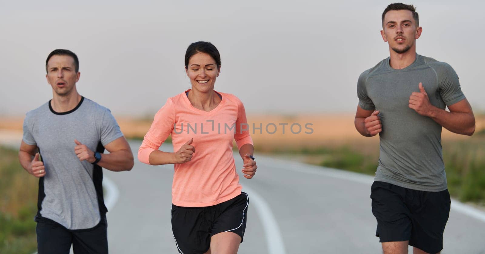 A group of friends, athletes, and joggers embrace the early morning hours as they run through the misty dawn, energized by the rising sun and surrounded by the tranquil beauty of nature.