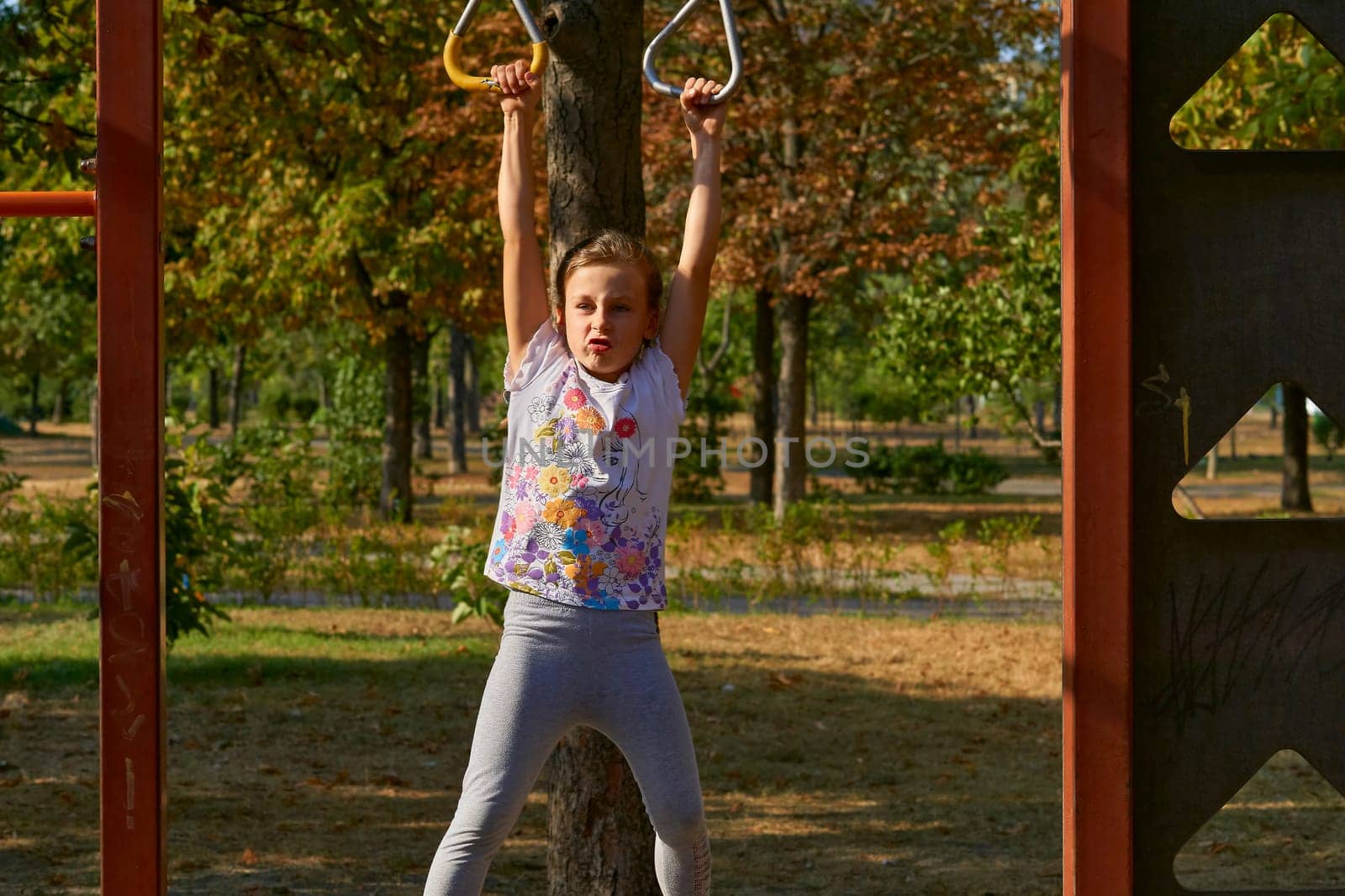 A cheerful child girl is working out on the horizontal bar, sports apparatus by jovani68