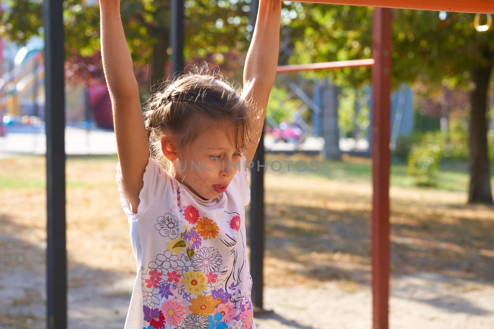 A cheerful child girl is working out on the horizontal bar, sports apparatus by jovani68