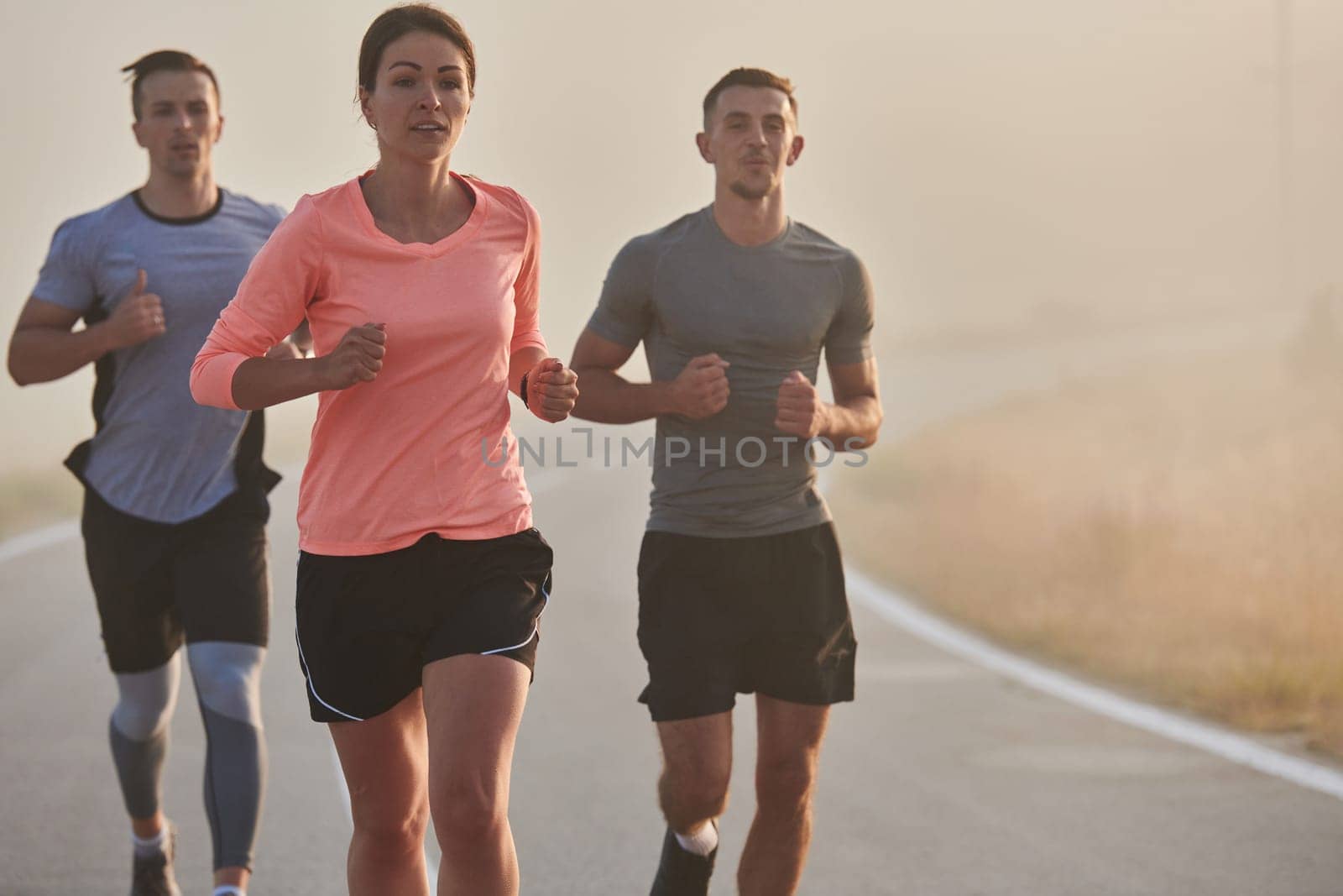 A group of friends, athletes, and joggers embrace the early morning hours as they run through the misty dawn, energized by the rising sun and surrounded by the tranquil beauty of nature by dotshock