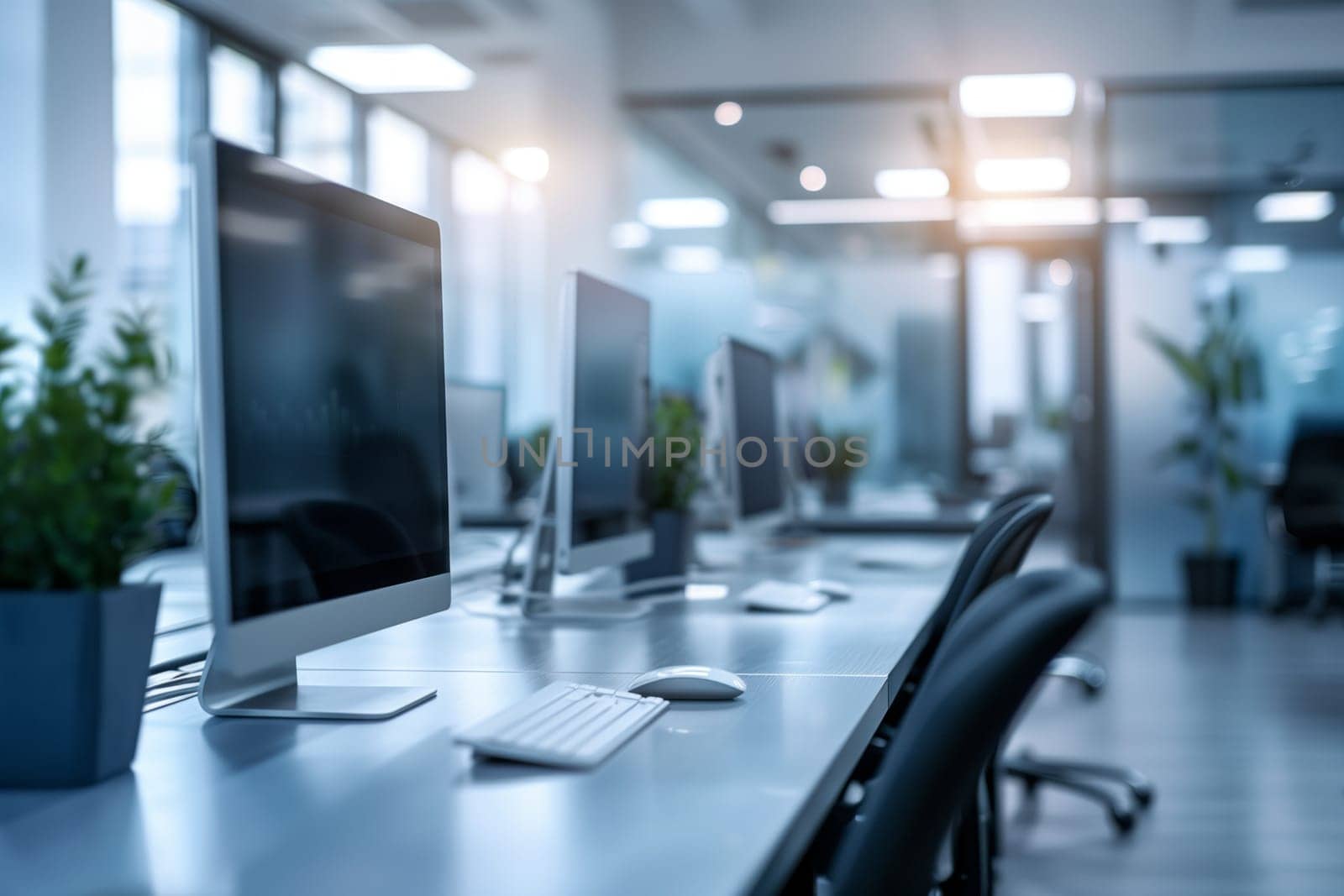 A row of computer monitors on a desk in an office building by richwolf