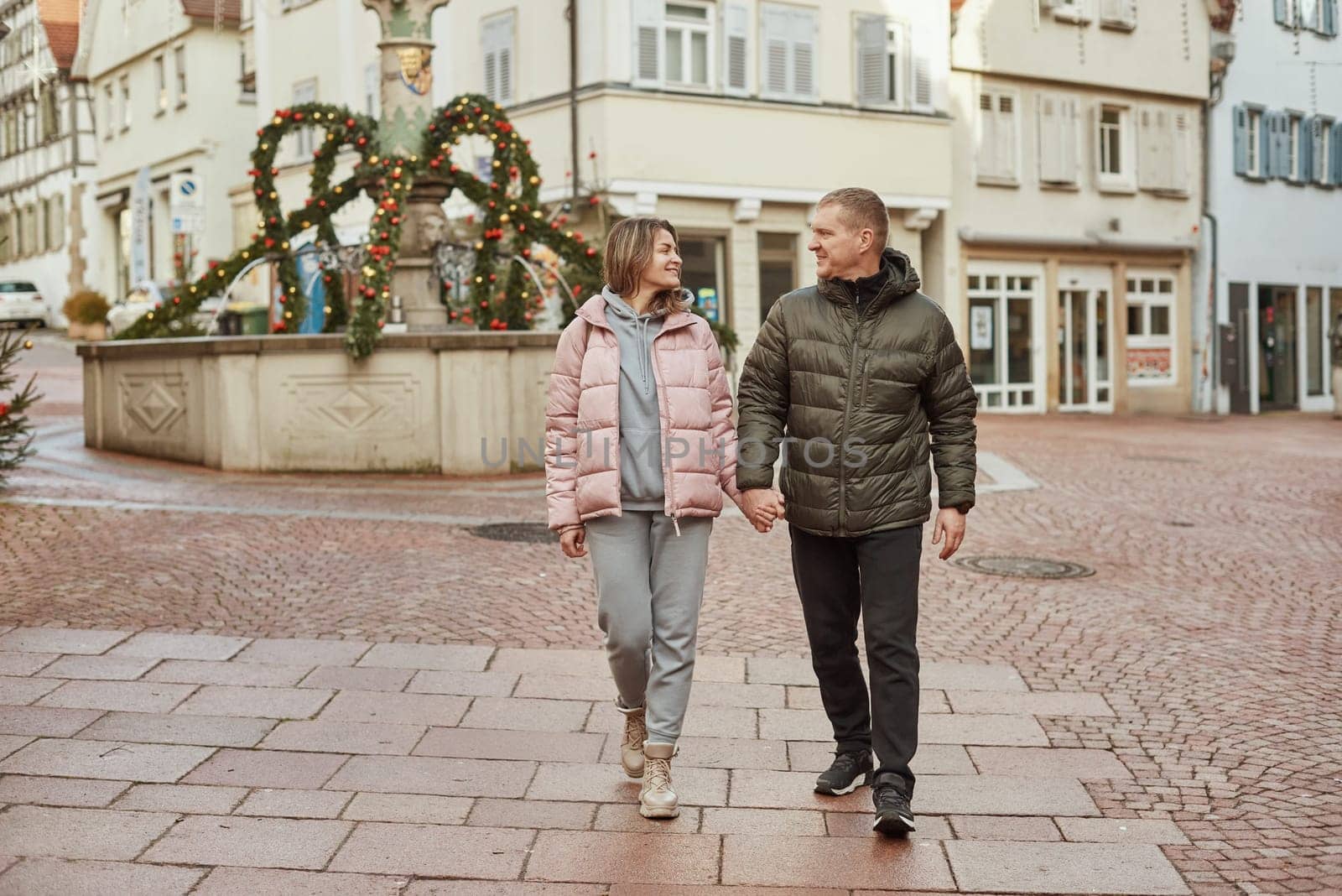 Loving couple of tourists walking around old town. Man woman couple walking europe old town Germany. Couple of lovers leisurely stroll in the cool autumn morning on the streets of a BIETIGHEIM-BISSINGEN (Germany). The guy holds his wife. Vacation, autumn, holiday. Couple Walking in Europe's Old Town