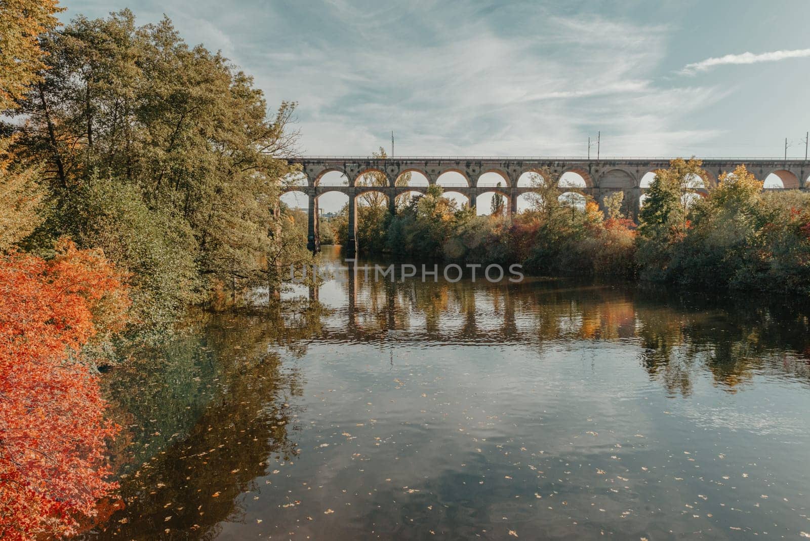 Railway Bridge with river in Bietigheim-Bissingen, Germany. Autumn. Railway viaduct over the Enz River, built in 1853 by Karl von Etzel on a sunny summer day. Bietigheim-Bissingen, Germany. Old viaduct in Bietigheim reflected in the river. Baden-Wurttemberg, Germany. Train passing a train bridge on a cloudy day in Germany by Andrii_Ko