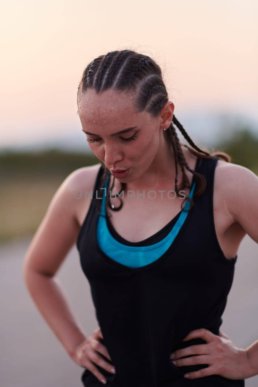 A close-up captures the raw dedication of a female athlete as she rests, sweat glistening, after a rigorous running session, embodying the true spirit of perseverance and commitment to her fitness journey