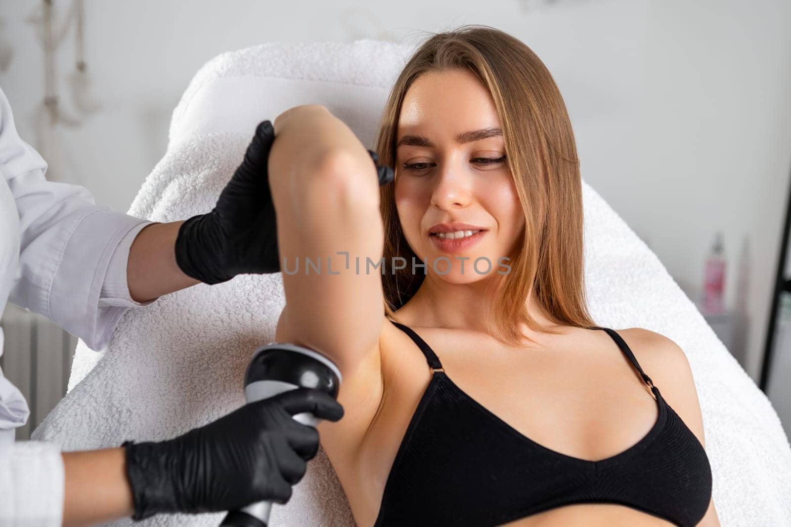 A blonde woman receiving an ultrasound cavitation treatment of her arm at a beauty salon. by vladimka