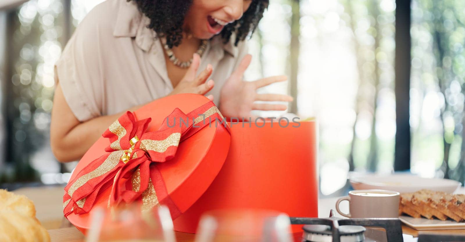 Woman, excited and open gift box in home with surprise, romance and love in marriage on valentines day. Lady, nervous and shake a red present for anniversary, care and gratitude by kitchen counter.