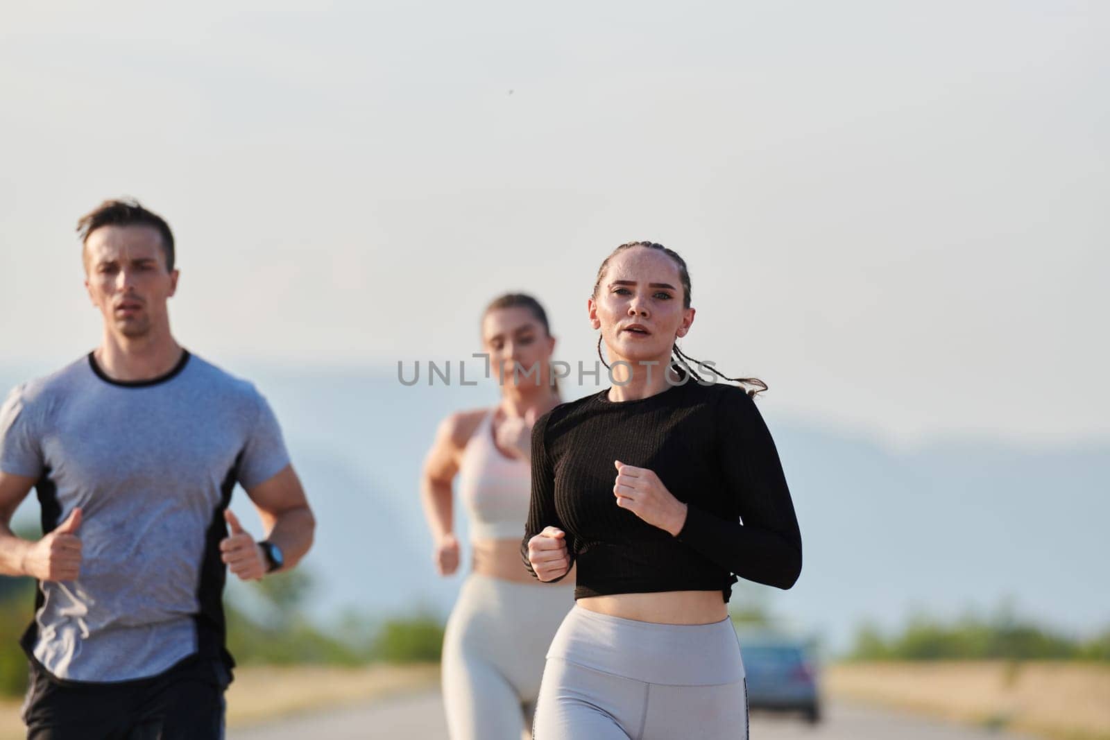 A group of friends maintains a healthy lifestyle by running outdoors on a sunny day, bonding over fitness and enjoying the energizing effects of exercise and nature.