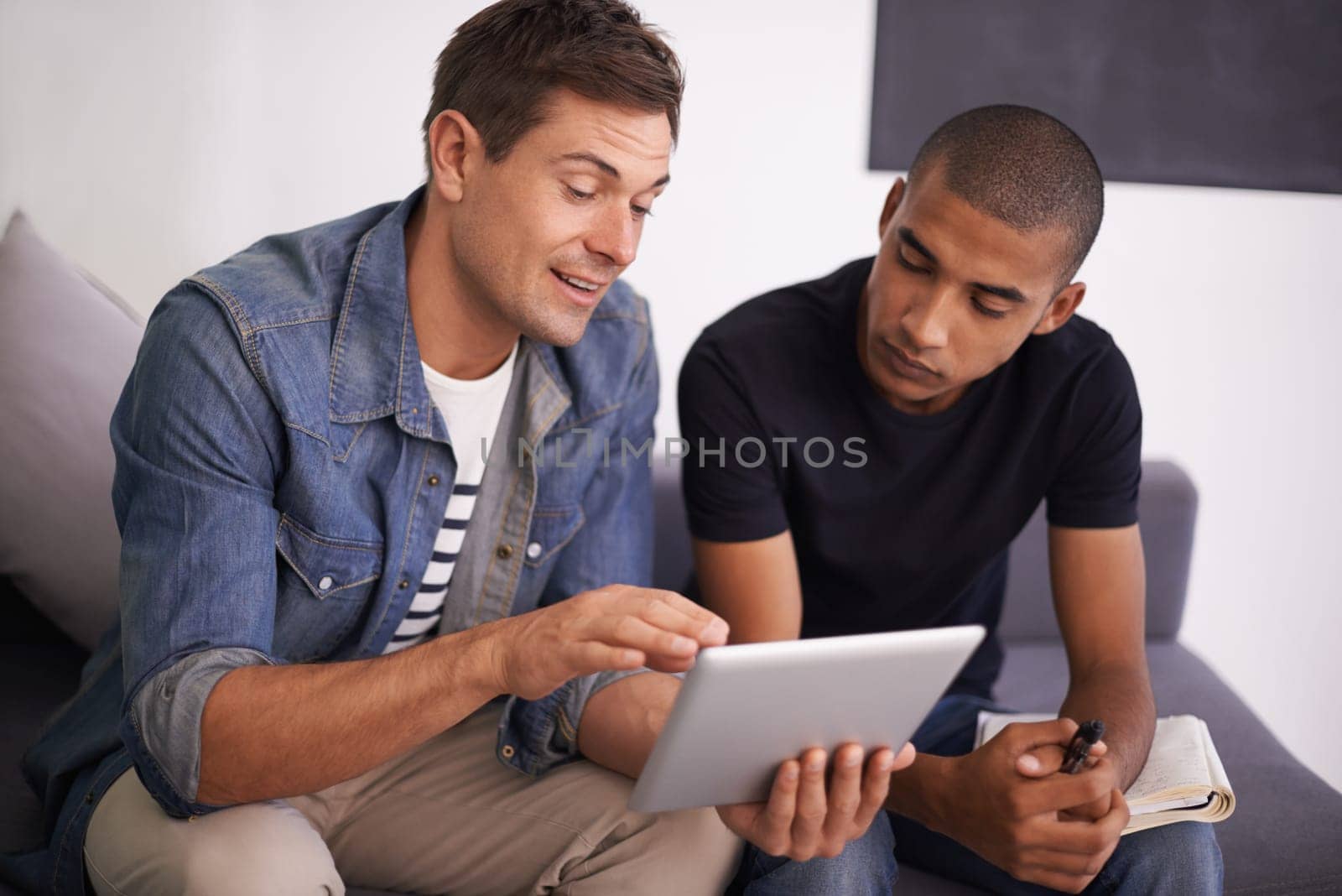 Men, sofa and tablet in office with discussion for research, creative startup and feedback on project. Employees, communication and technology with notebook for planning, networking and brainstorming.