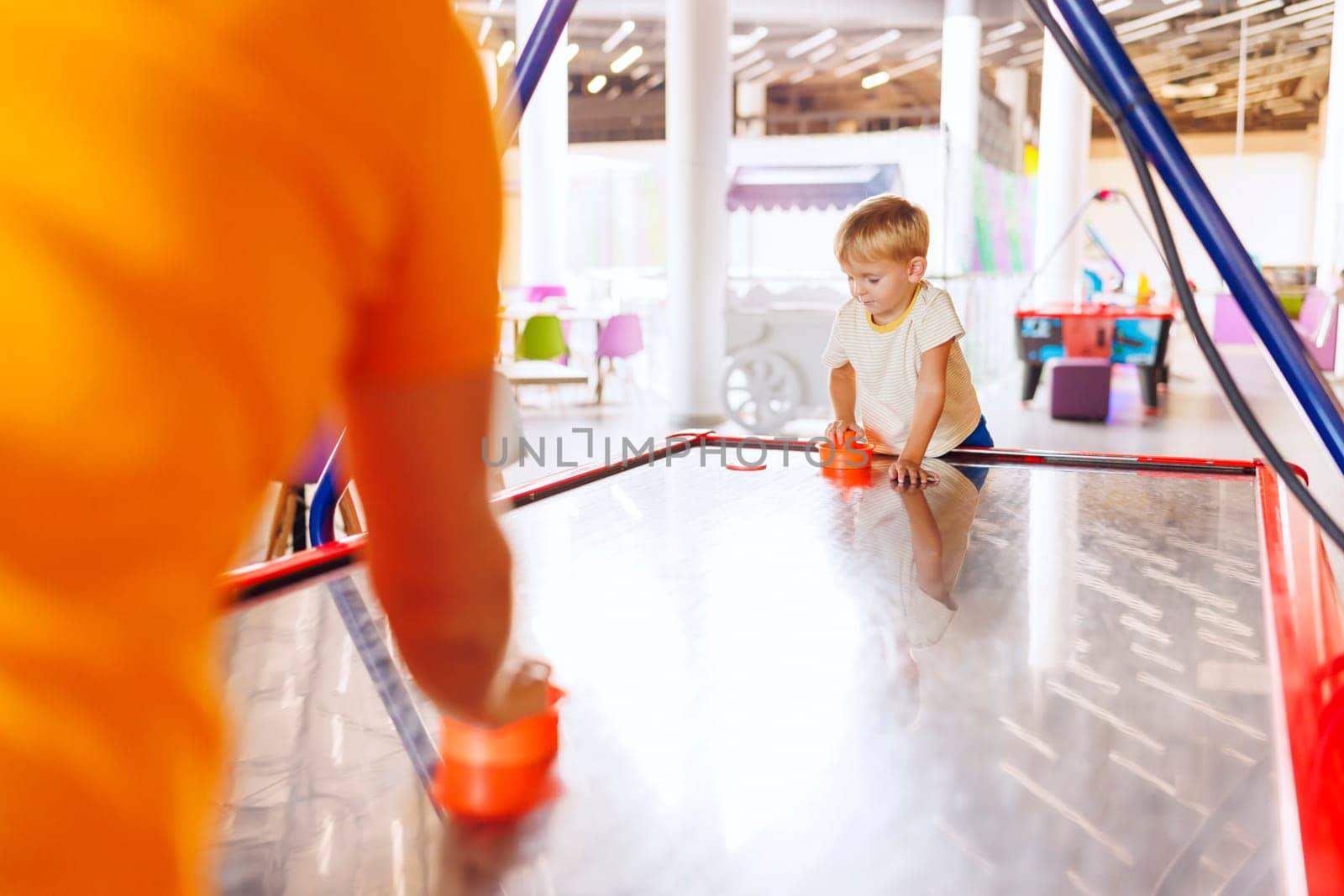 Boy playing air hockey in indoor play area. by andreyz