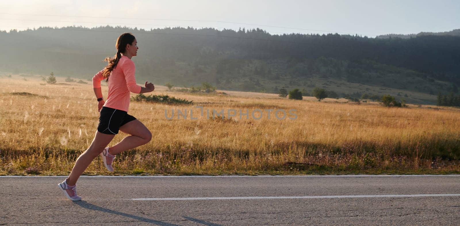 A resolute and motivated athlete running confidently into the sunrise, epitomizing determination and empowerment in her early morning run.