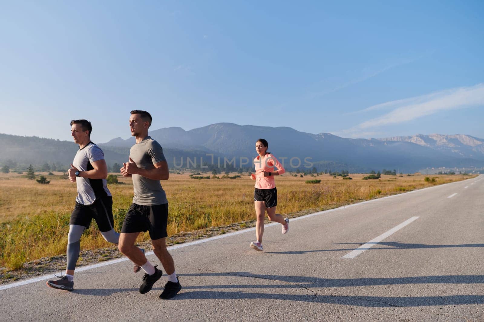 A group of friends maintains a healthy lifestyle by running outdoors on a sunny day, bonding over fitness and enjoying the energizing effects of exercise and nature by dotshock