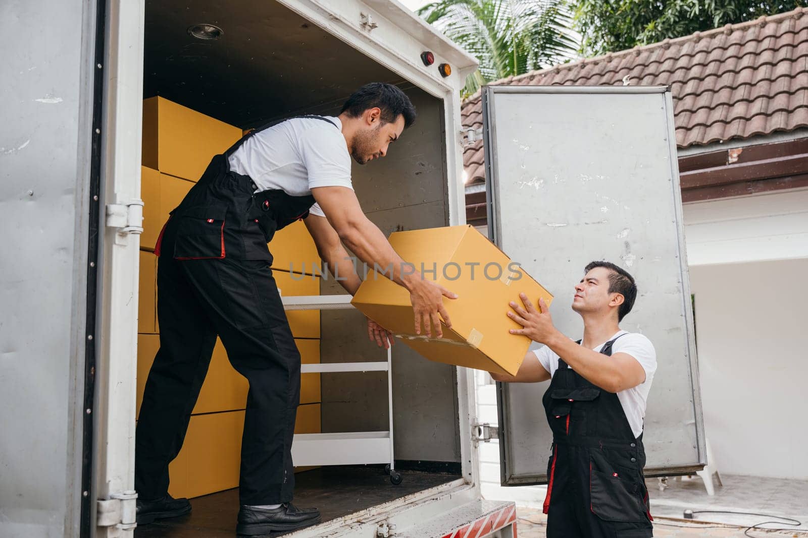 Teamwork in action, workers unload boxes from the moving truck for customer relocation. The company dedication ensures a smooth move and happiness. Moving Day