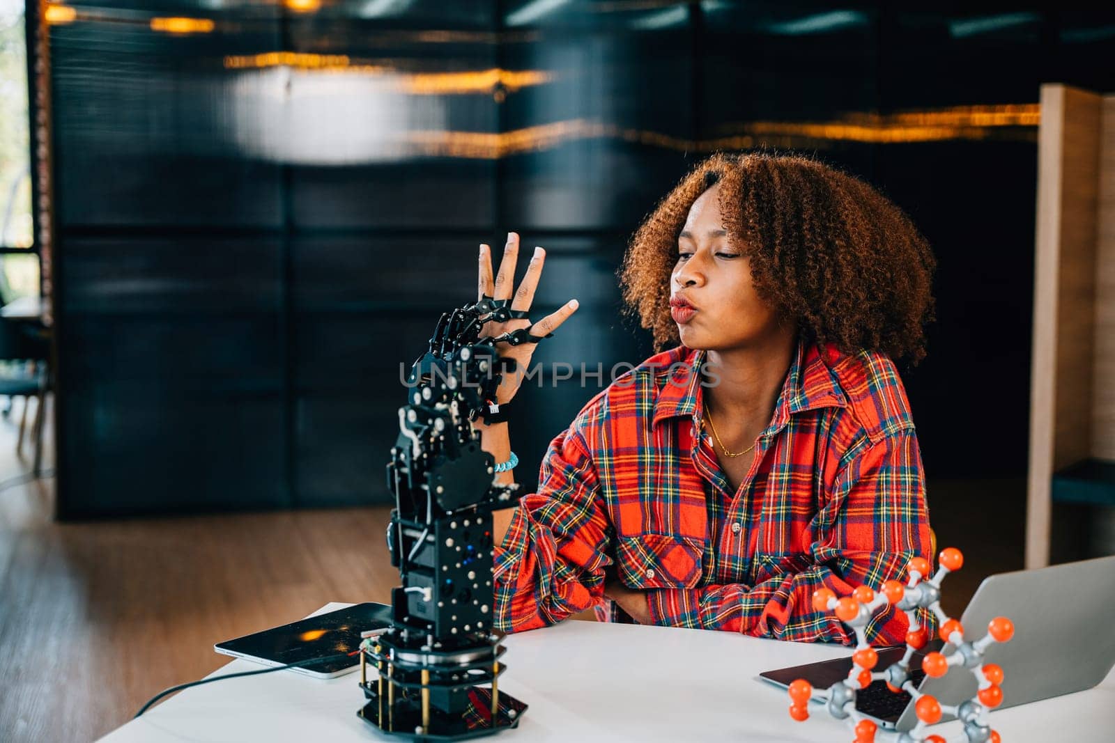 In a classroom a smart teenager experiments with a humanoid robotic hand showcasing joy in learning. Portraying education innovation and skill development in technology. Robot hand. Innovation concept by Sorapop