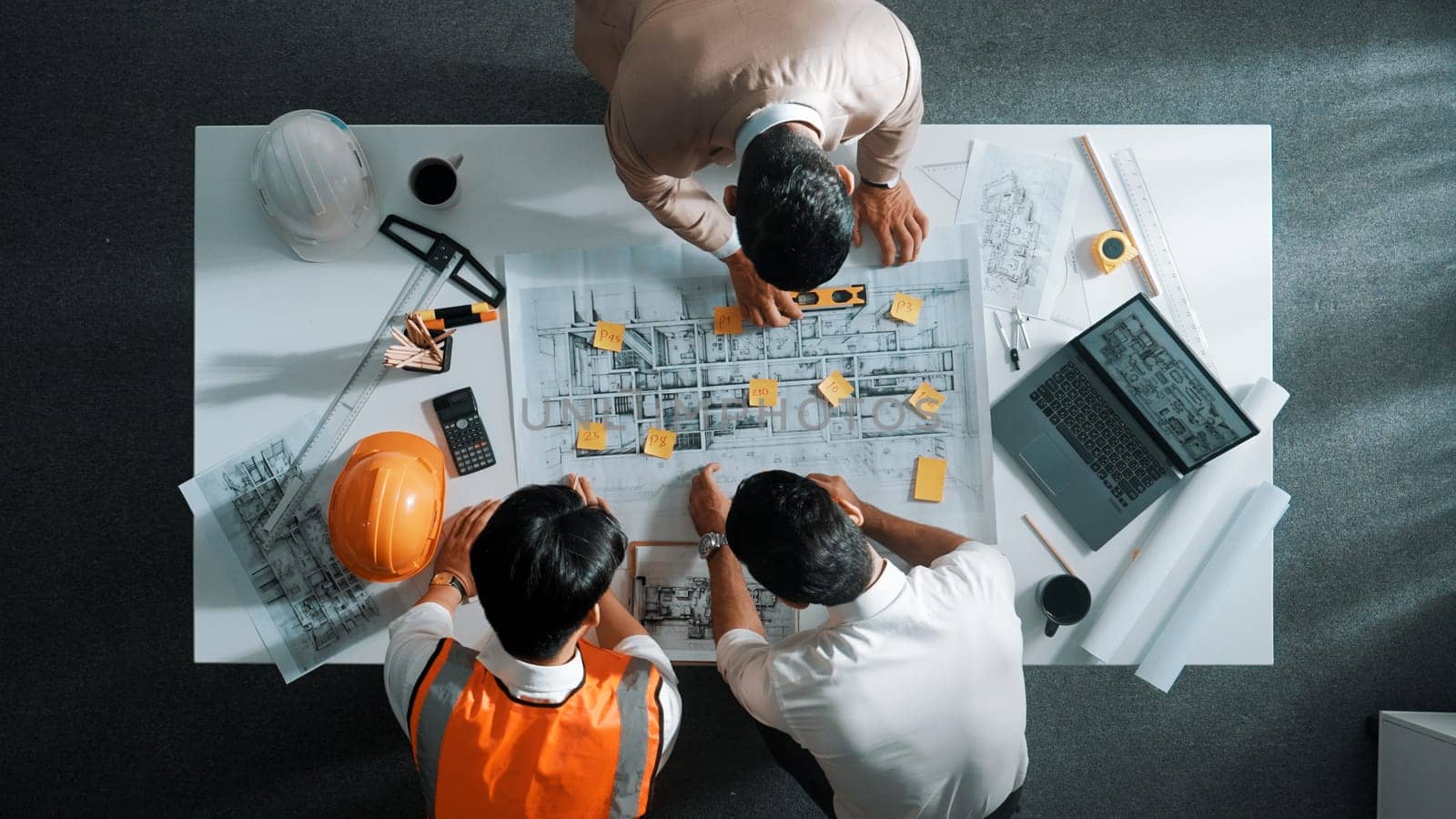 Top down aerial view of smart architect engineer team pointing and discussing about building construction. Group of diverse people working together to plan and design by using blueprint. Alimentation.