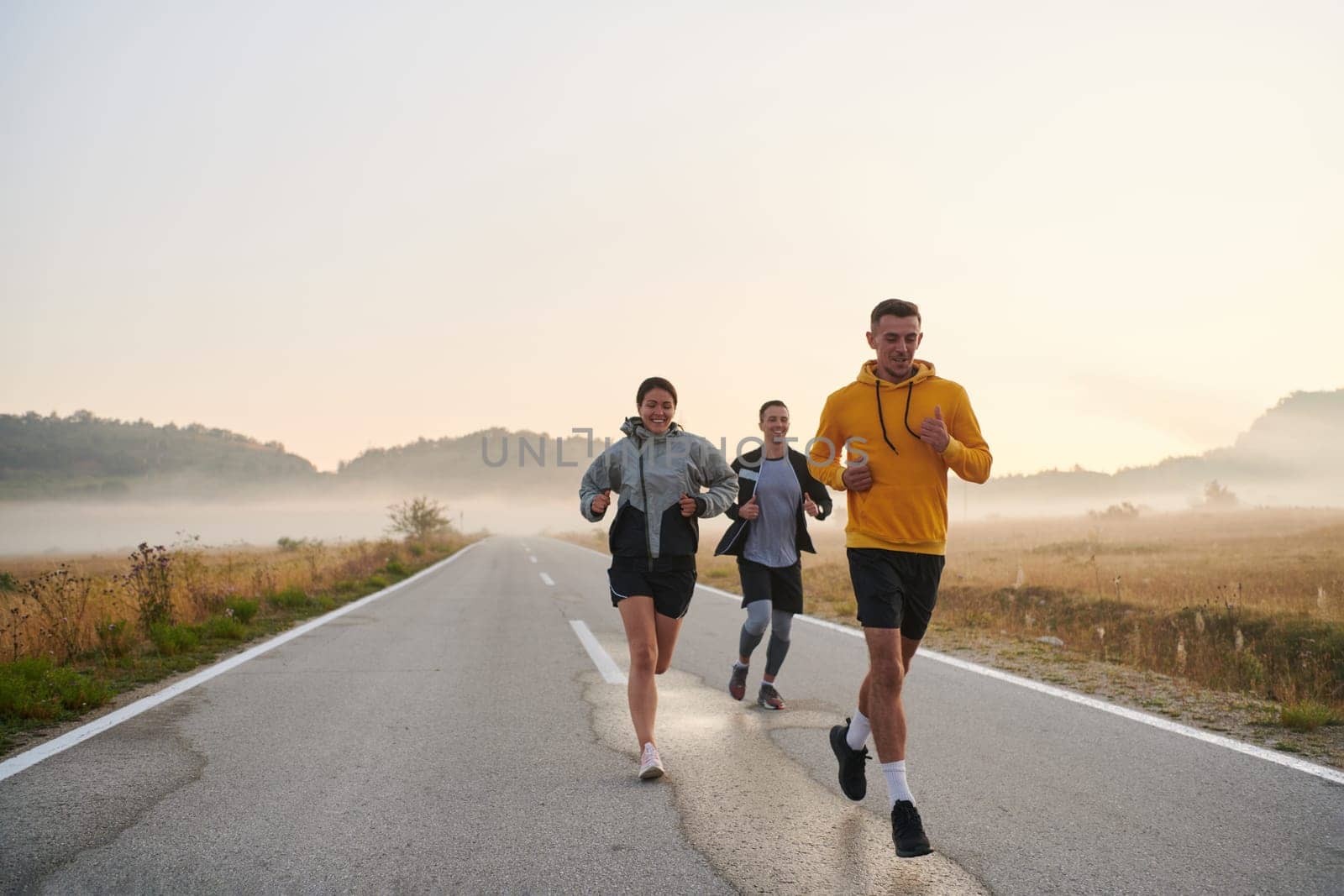 A group of friends, athletes, and joggers embrace the early morning hours as they run through the misty dawn, energized by the rising sun and surrounded by the tranquil beauty of nature by dotshock