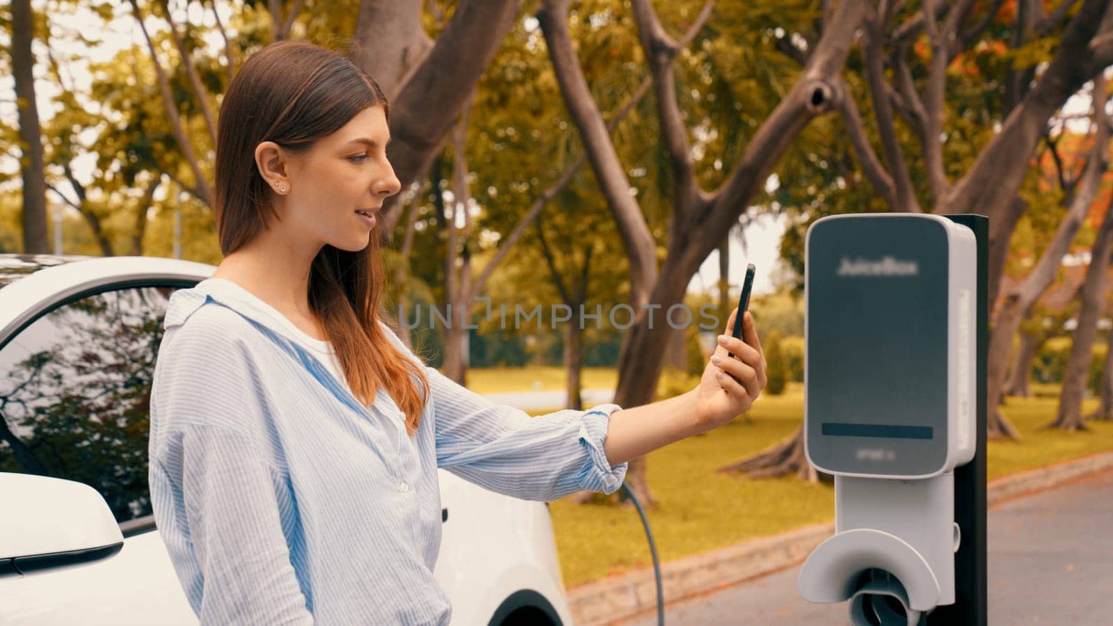 Woman using smartphone to pay for electric car charging. Exalt by biancoblue