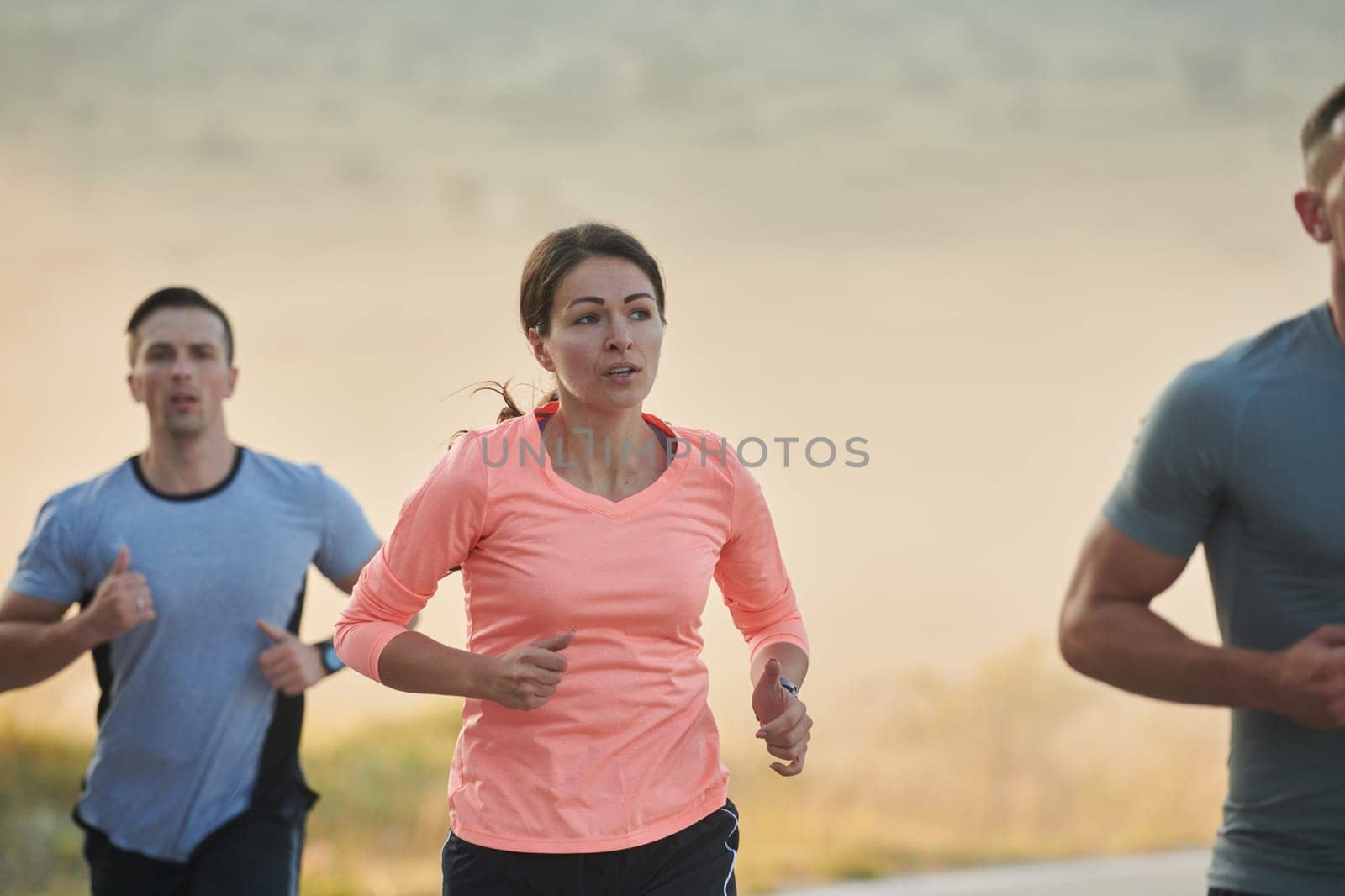 A group of friends, athletes, and joggers embrace the early morning hours as they run through the misty dawn, energized by the rising sun and surrounded by the tranquil beauty of nature by dotshock