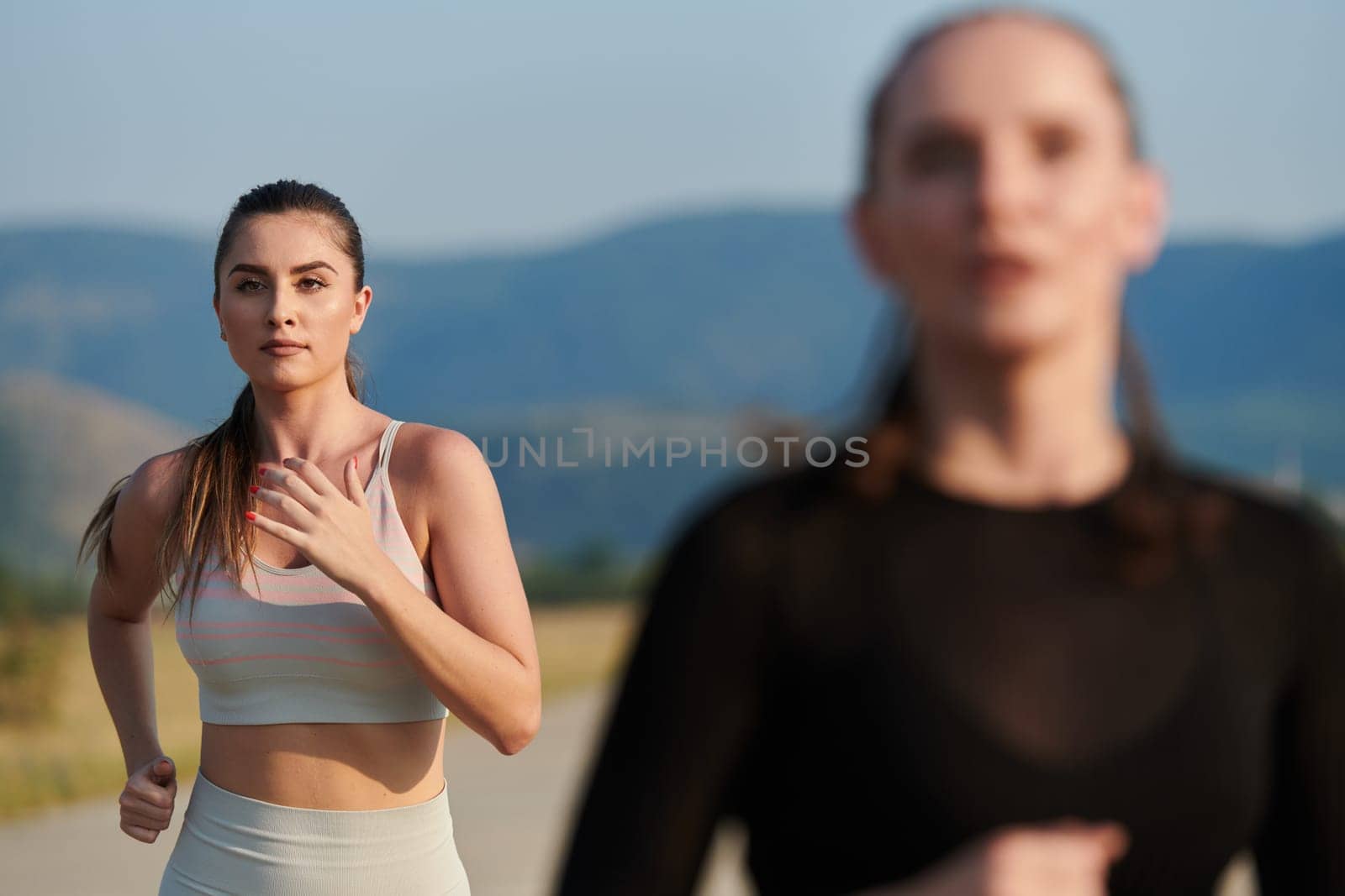 An athletic woman finds freedom and joy in a healthy lifestyle, running through a beautiful road trail at sunrise.