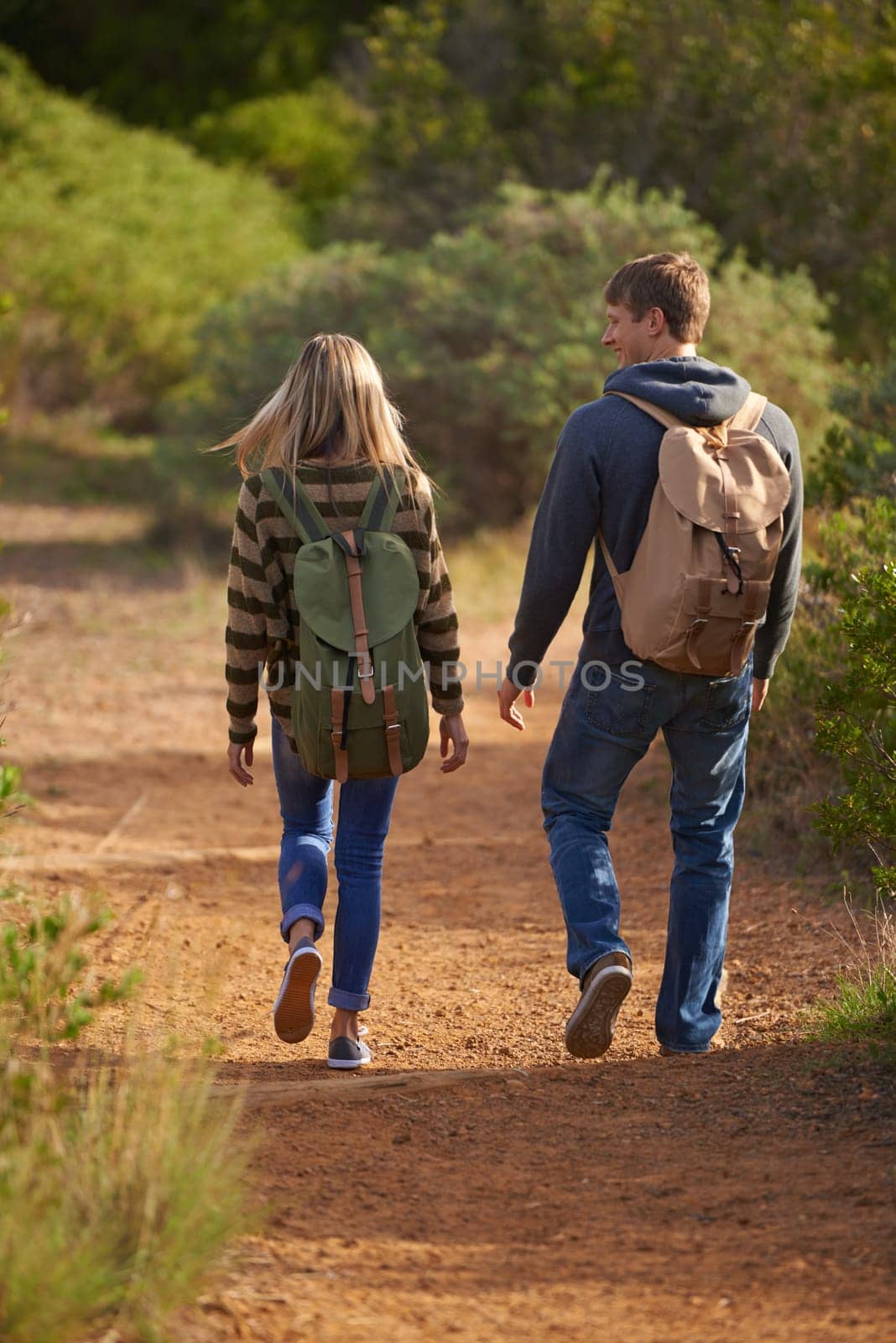 Path, hiking and happy couple walking in nature for holiday, travel or adventure outdoor with backpack. Rear view, man and woman trekking in the countryside on vacation, journey and date together.