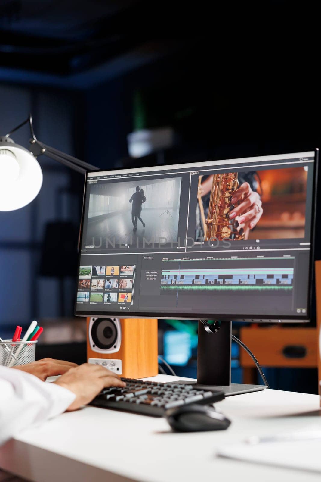 Male cinematographer working with footage and sound, editing new project, cutting film montage seated at office desk. Detailed view of man using computer processing movie in post production software.