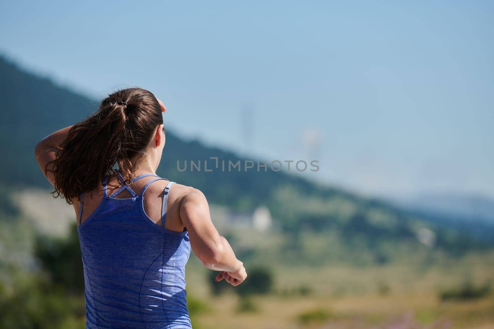 An athletic woman finds freedom and joy in a healthy lifestyle, running through a beautiful road trail at sunrise.