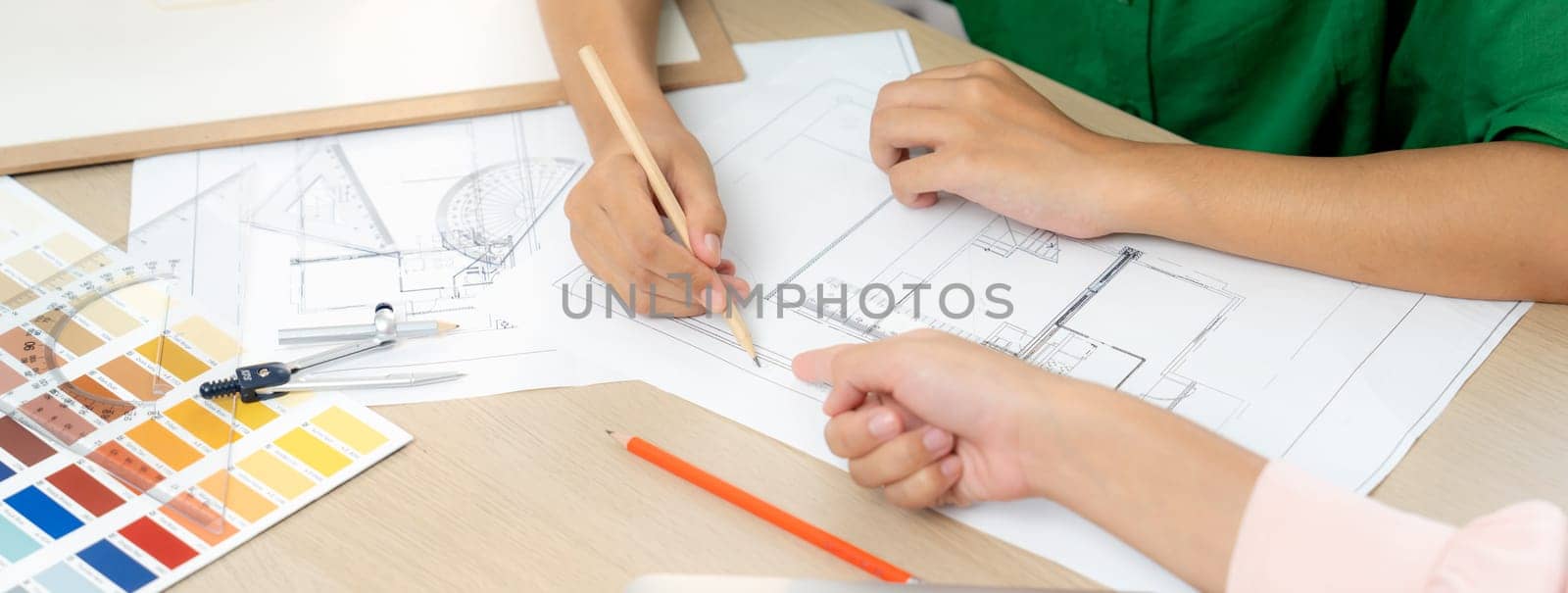 Professional architect drafts blueprint from project manager advice on table with house model, color palette and architectural equipment. Creative design concept. Focus on hand. Closeup. Variegated.