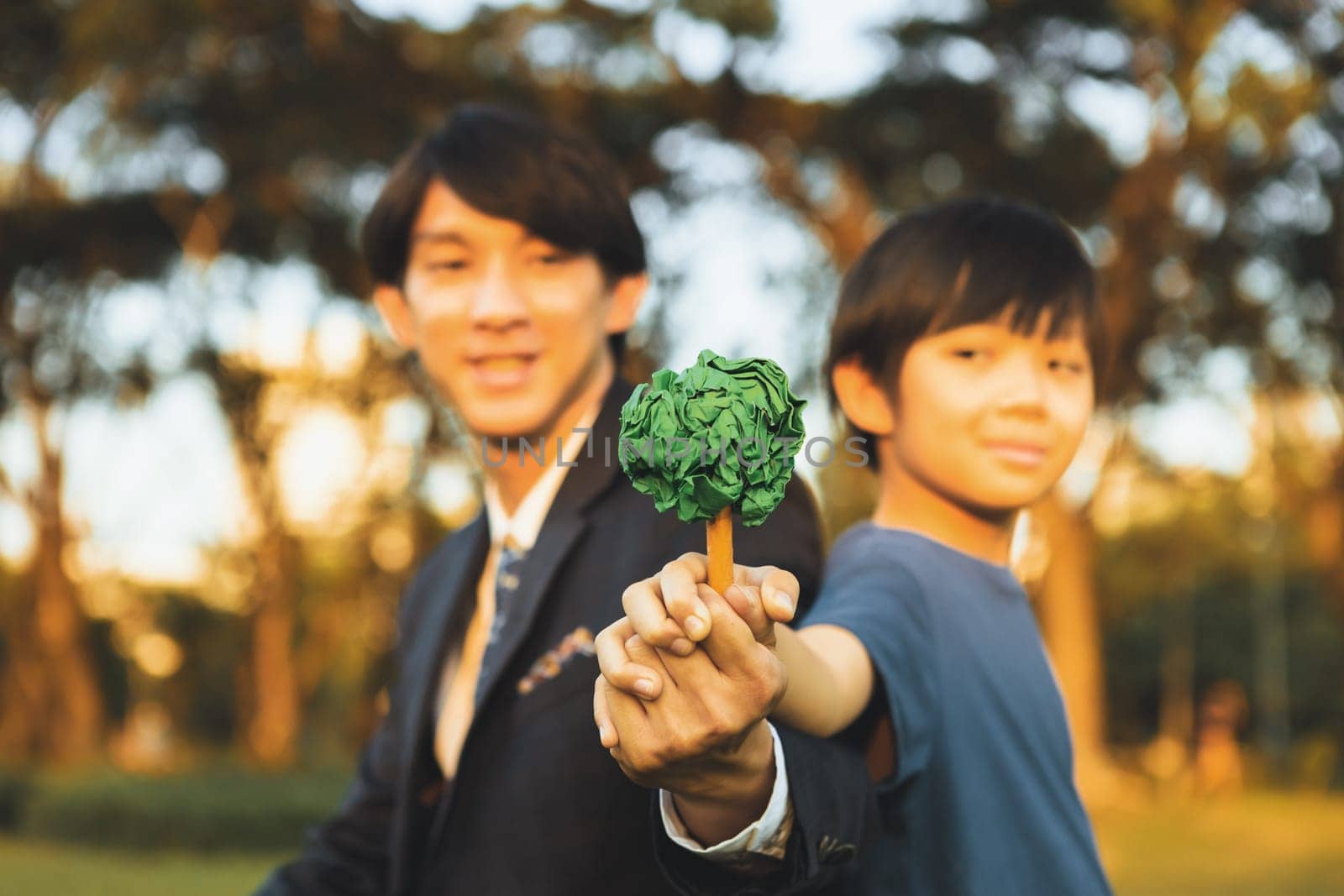 Asian boy and businessman holding paper tree together as Earth day concept as corporate social responsible to make greener environmental protection for sustainable future generation. Gyre