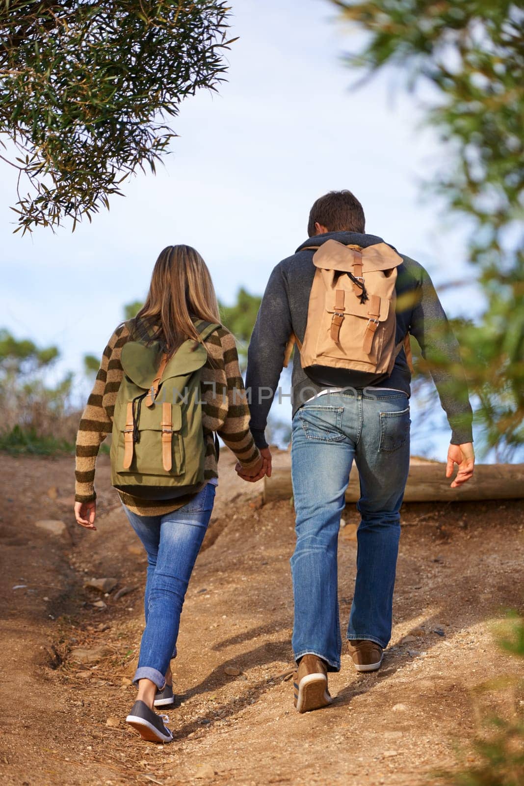 Path, hiking and couple holding hands in nature for holiday, travel or adventure outdoor with backpack. Rear view, man and woman trekking in the countryside on vacation, journey and date together.