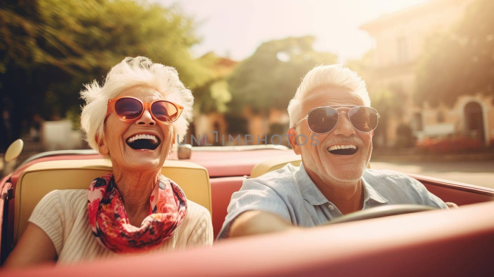 A smiling couple in a red convertible, enjoying a sunny day drive. The woman wears a red scarf, the man a blue shirt. No other cars on the road, surrounded by lush green trees.