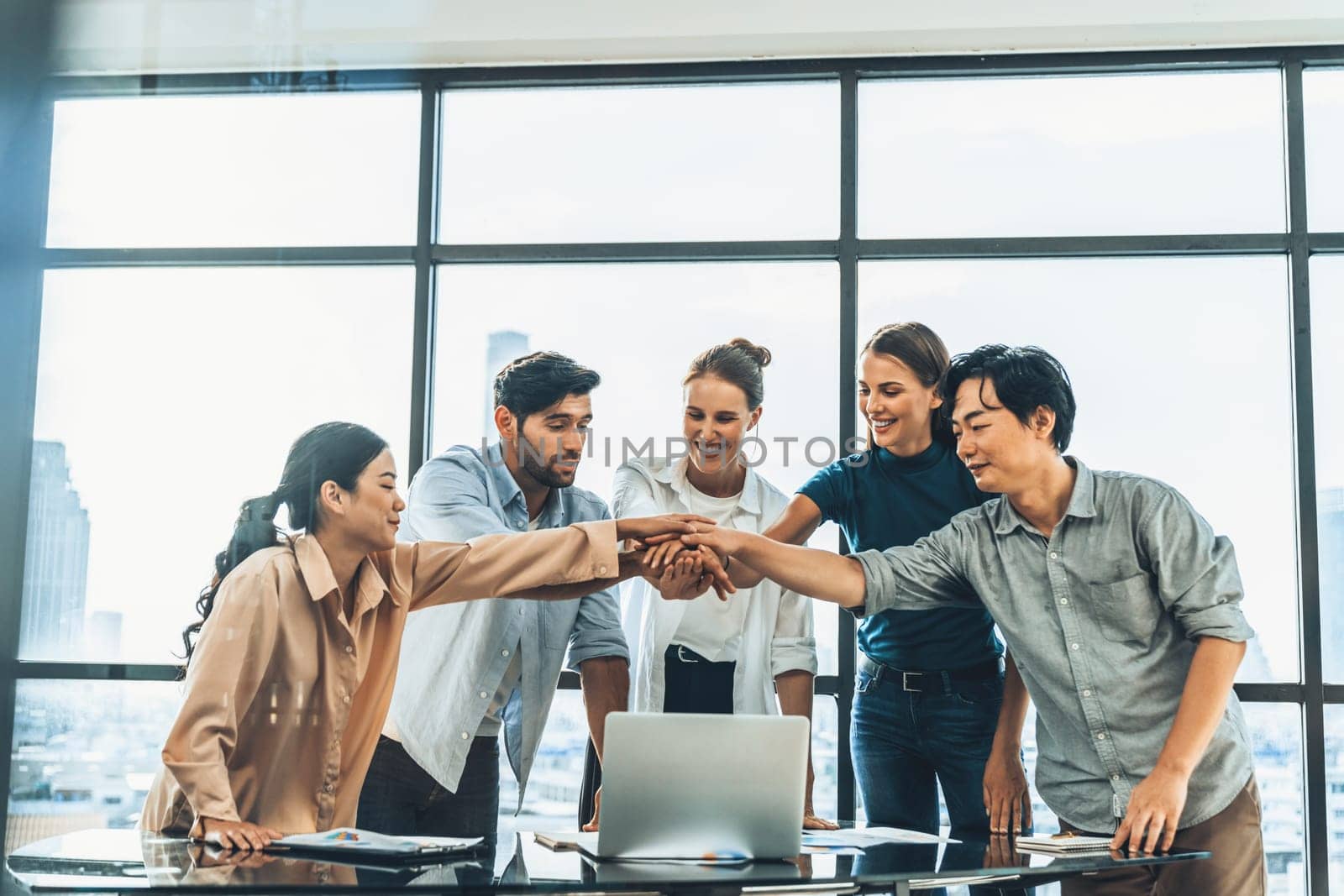 Group of multicultural businesspeople putting hands together at modern office. Happy smart business team working together. Represented unity, working together, partnership, work place. Tracery.