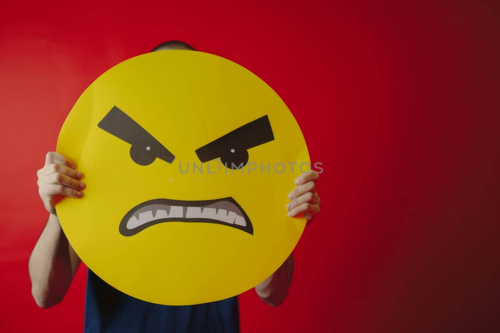 The girl holds a sign in front of her, a yellow emoticon of emotions.