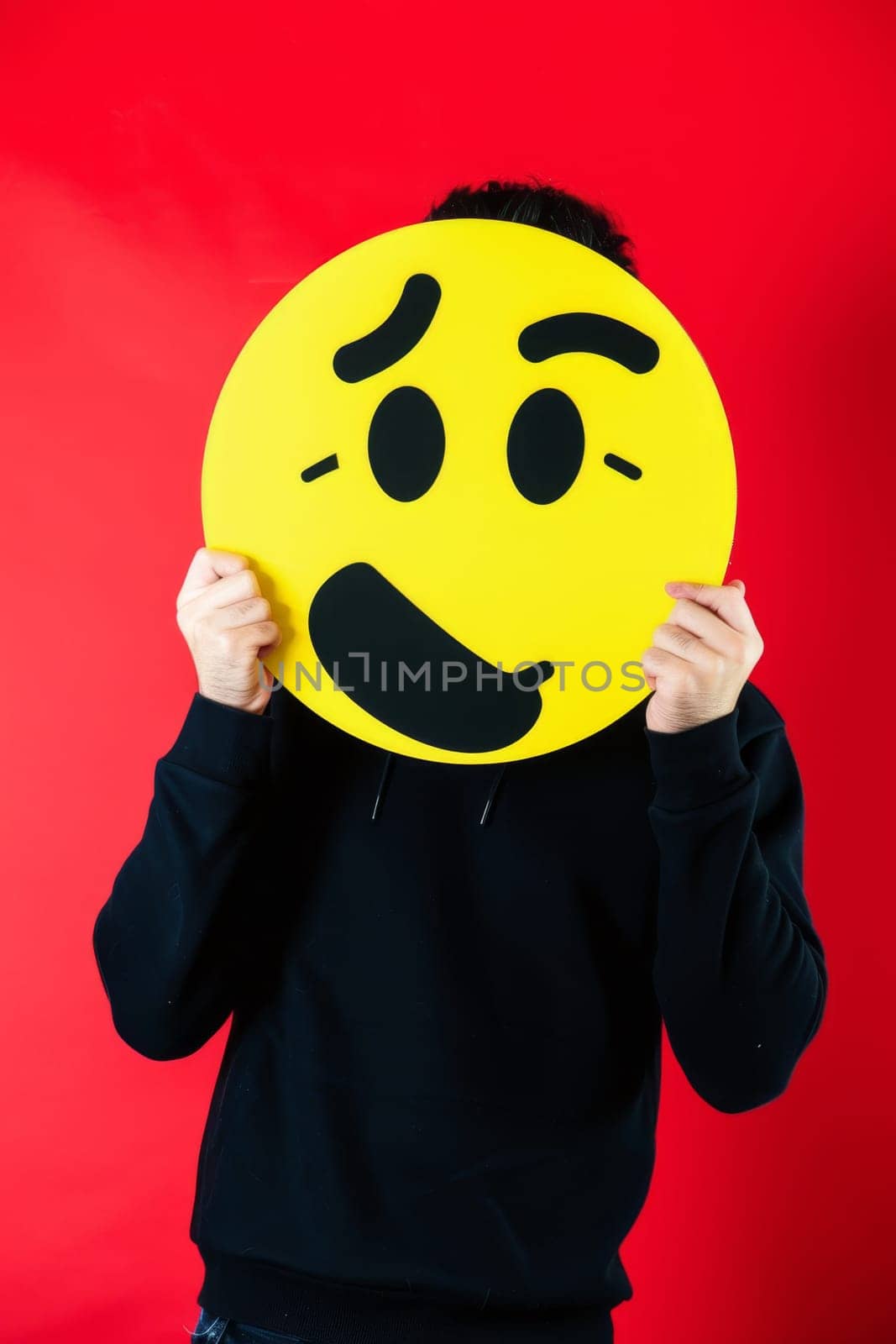 The girl holds a sign in front of her, a yellow emoticon of emotions.